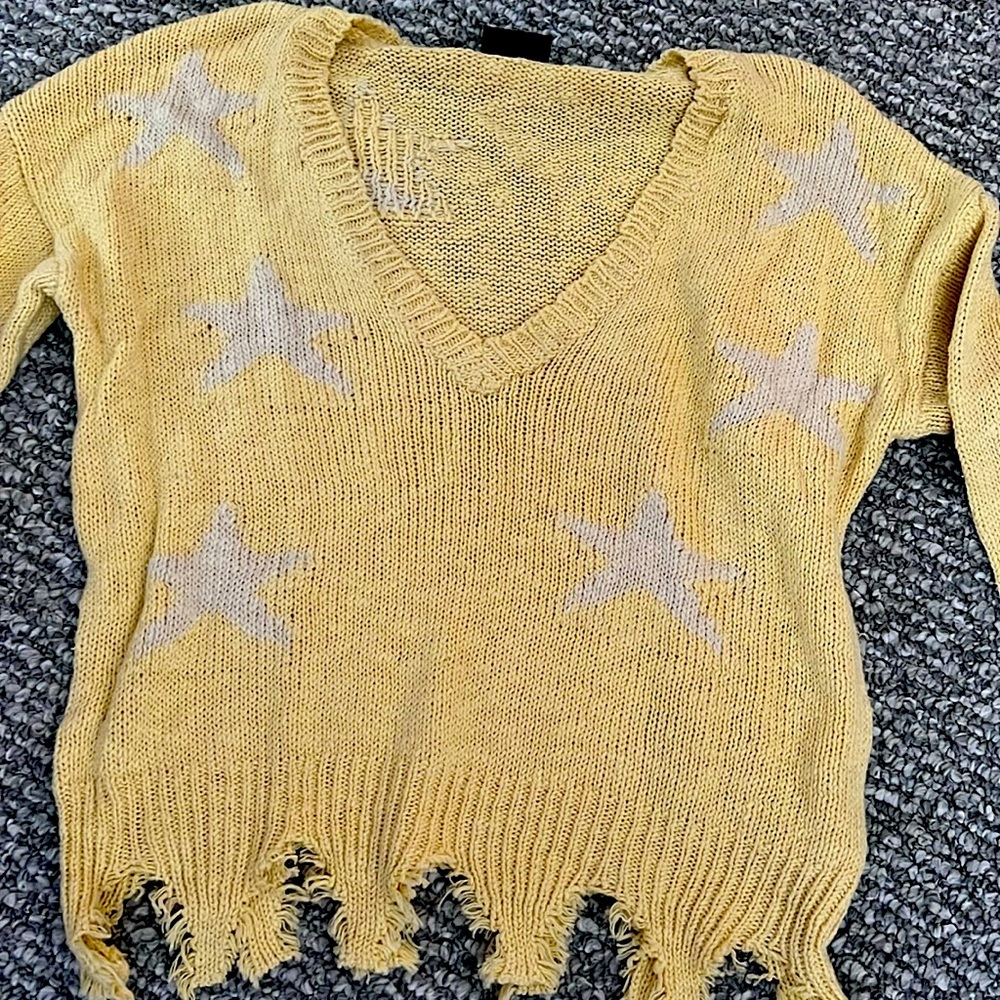 Pale, yellow sweater size, small medium with white stars, distressed bottom